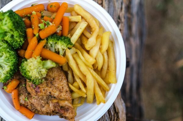 Delicious chicken dinner with broccoli, carrots, and fries on a plate.